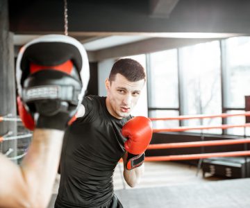 Homme s'entraînant avec un entraîneur de boxe sur le ring de boxe