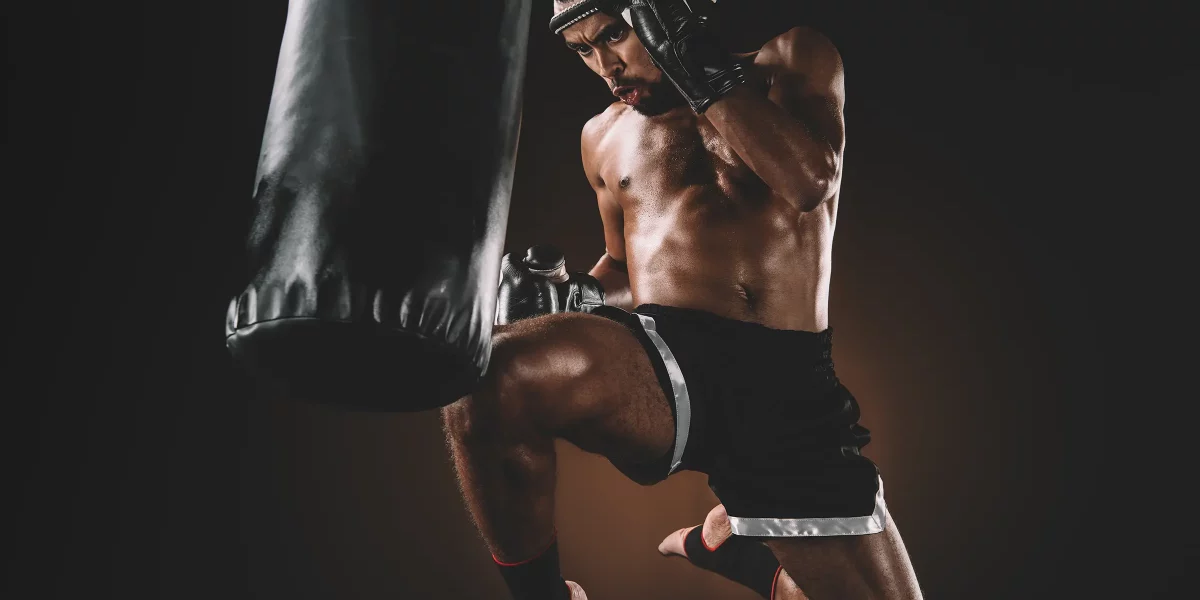 Combattant muay thai qui met un coup de genou sauté sur un sac de frappe