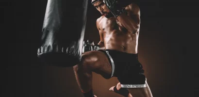 Combattant muay thai qui met un coup de genou sauté sur un sac de frappe